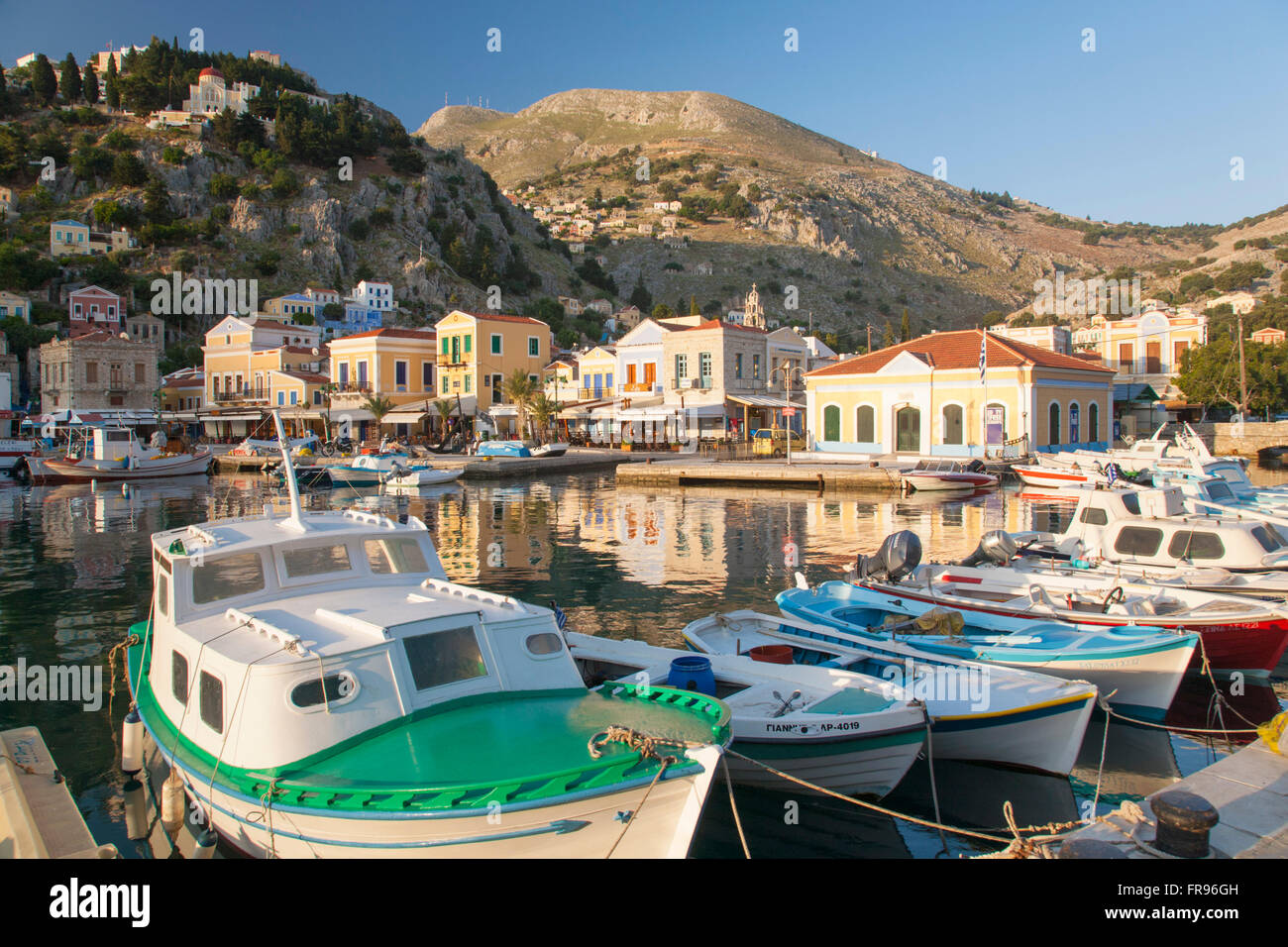 Gialos, Symi, Egeo Meridionale, Grecia. Vista attraverso il tranquillo porto, la mattina presto. Foto Stock