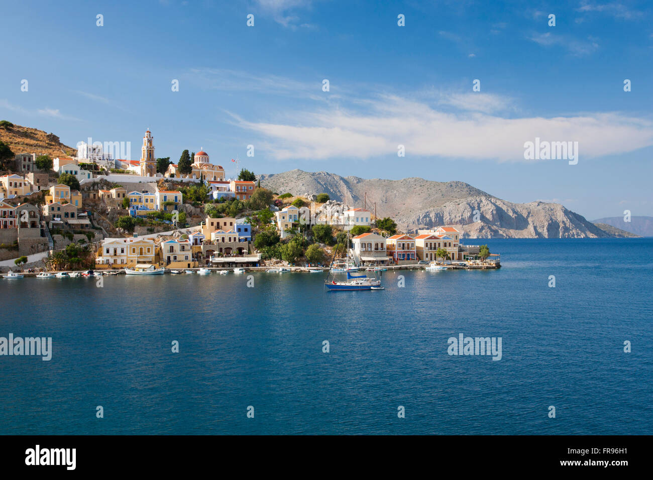 Gialos, Symi, Egeo Meridionale, Grecia. Vista attraverso le tranquille acque della baia di Harani. Foto Stock