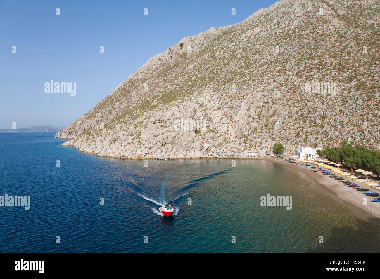 Pazienti pediatrici, Symi, Egeo Meridionale, Grecia. Accelerando in barca attraverso la baia riparata di Agios Nikolaos. Foto Stock