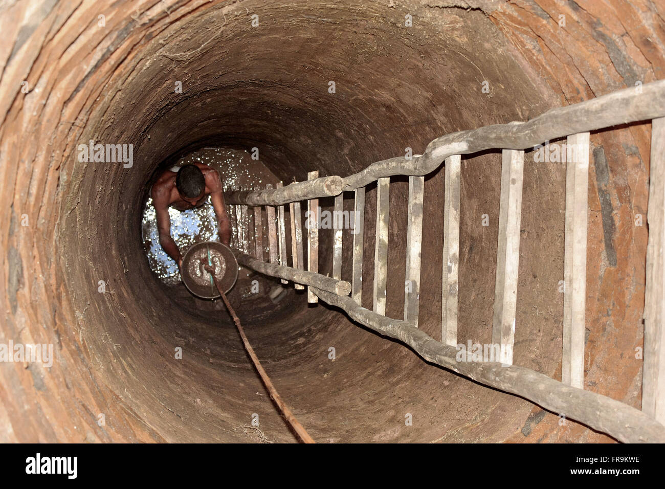 Un residente di poco rurale scavare per rimuovere l'acqua dal sottosuolo Foto Stock