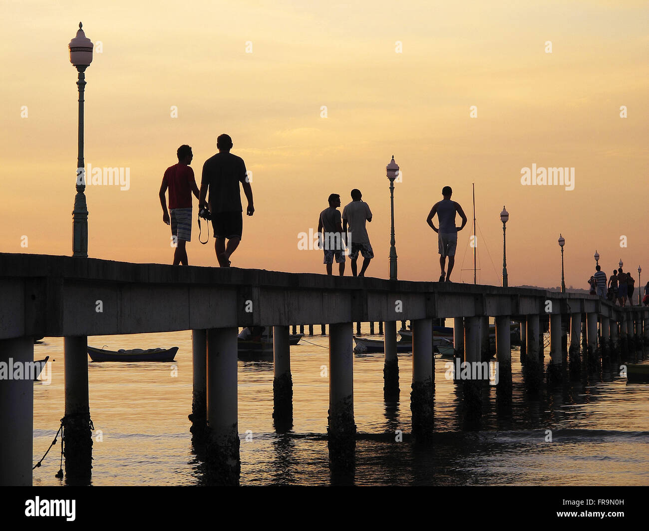 I turisti a piedi nel tardo pomeriggio sul molo dalla spiaggia di Manguinhos a Armacao dos Buzios Foto Stock