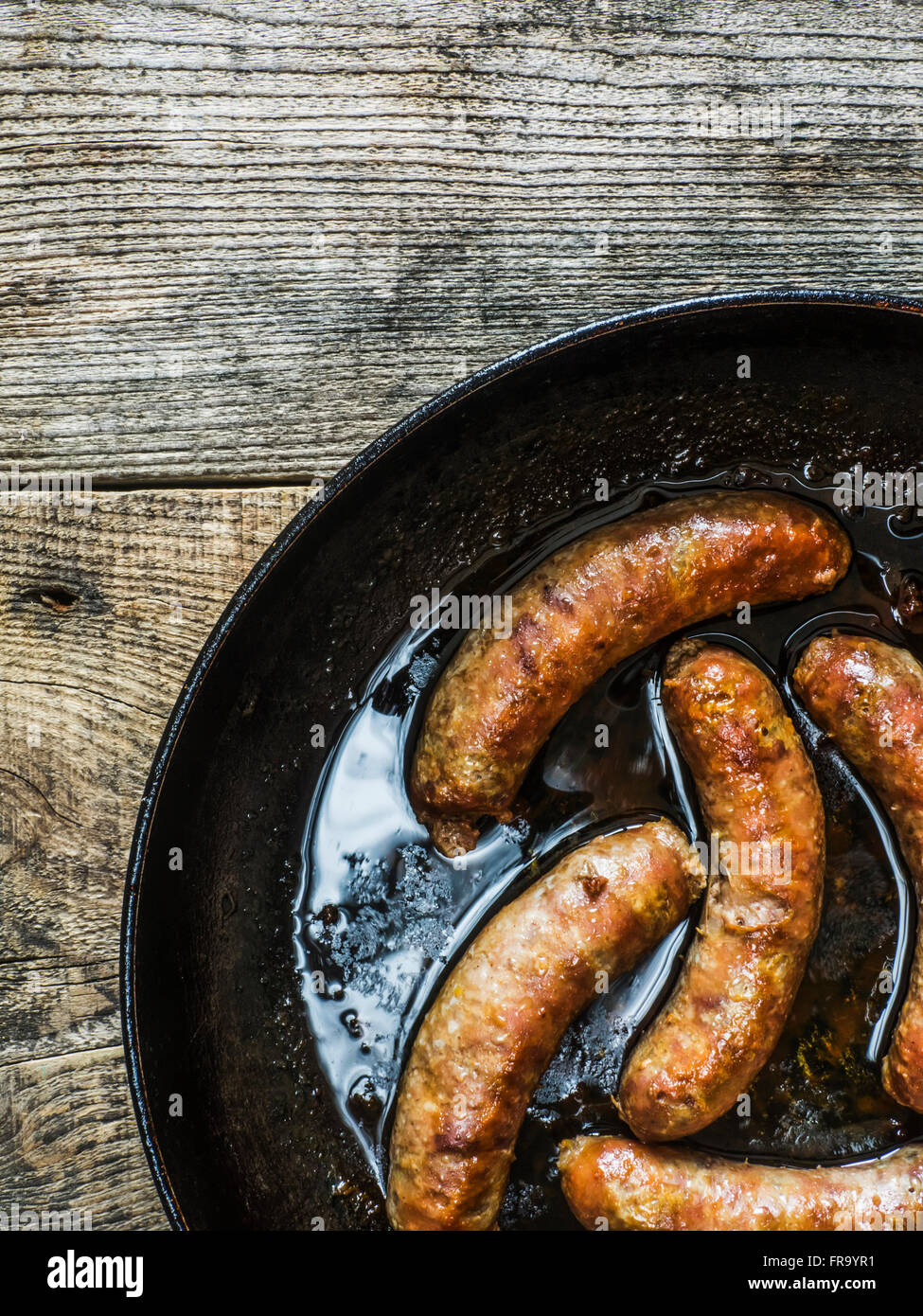 Fried salsicce fatte in casa in coppa sul vecchio weathered tavolo in legno; Kiev, Ucraina Foto Stock
