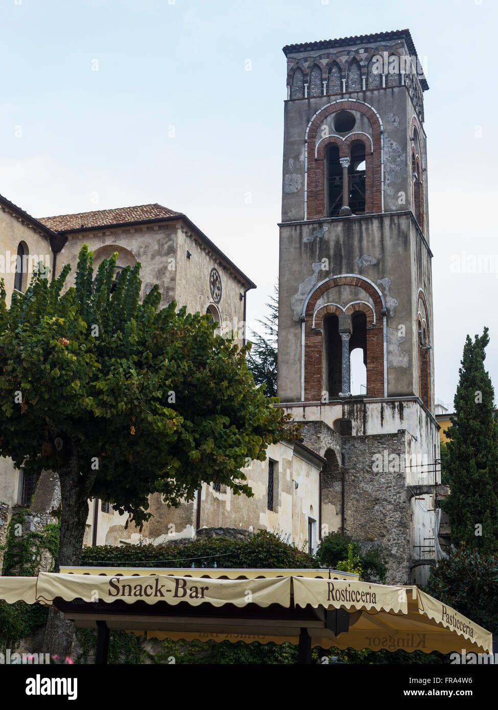 Una torre contro un cielo blu con nuvole e una tenda per uno snack bar verso il basso al di sotto; Ravello, Italia Foto Stock