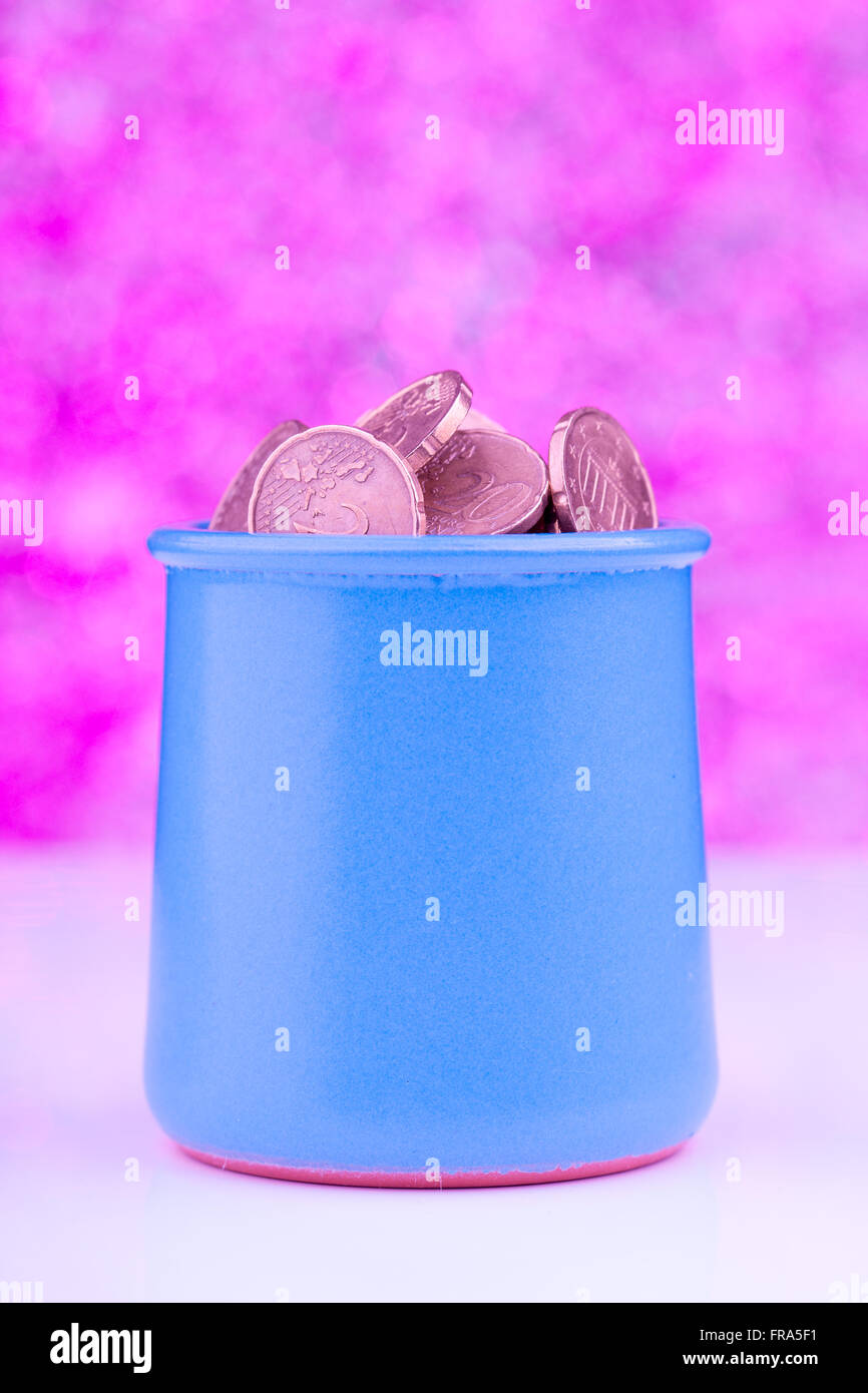 Vaso blu con le monete su sfondo rosa Foto Stock
