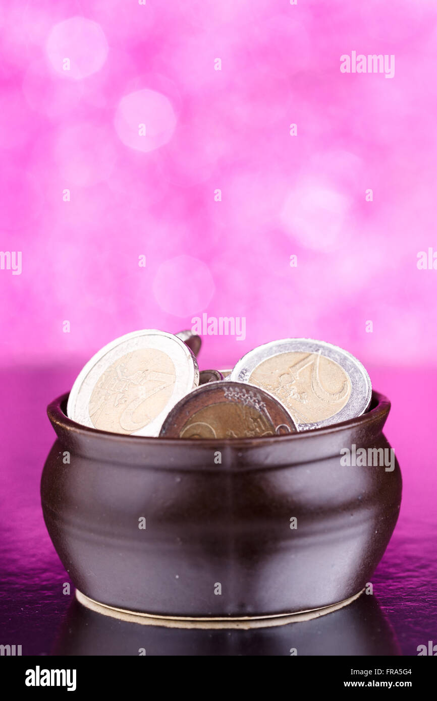 Pot marrone con monete su sfondo rosa Foto Stock