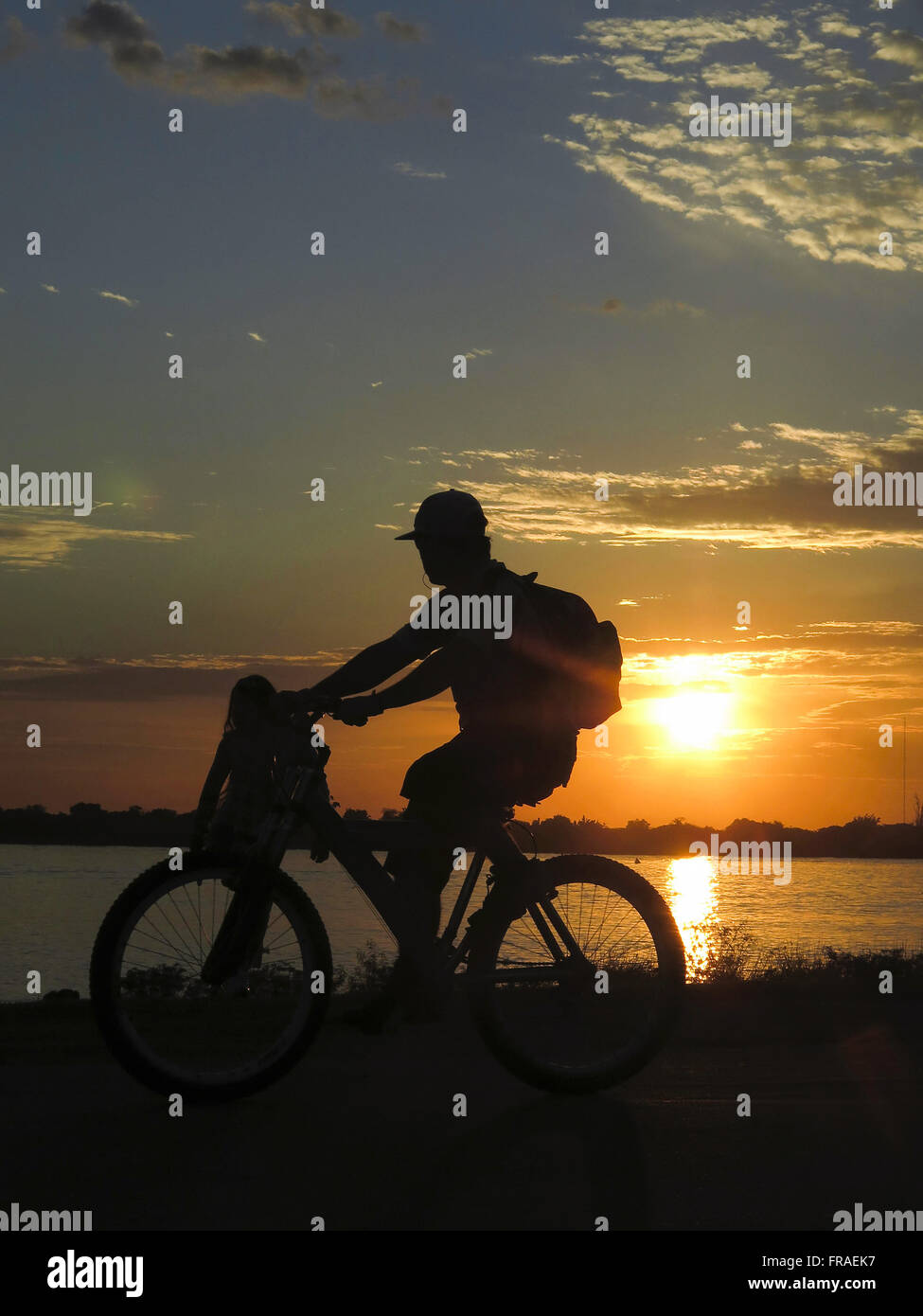 Ciclista orologi il tramonto sulla riva del lago Guaiba downtown Foto Stock