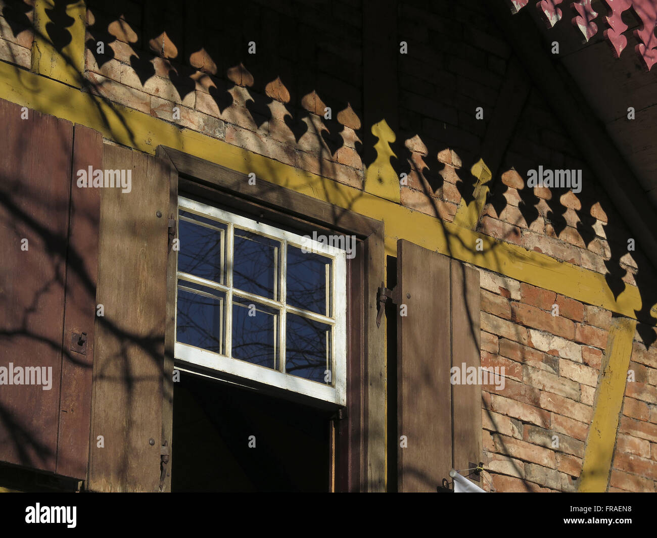 Chiudere la finestra in legno e tonalità di gronda la casa di mattoni a vista Foto Stock