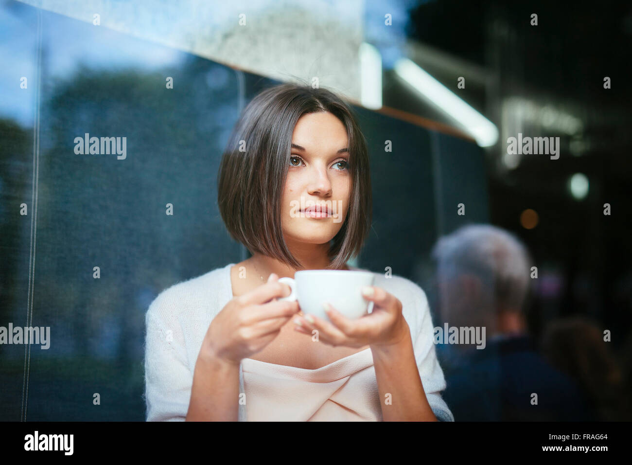 Bella donna con tazza di caffè ristorante finestra Foto Stock