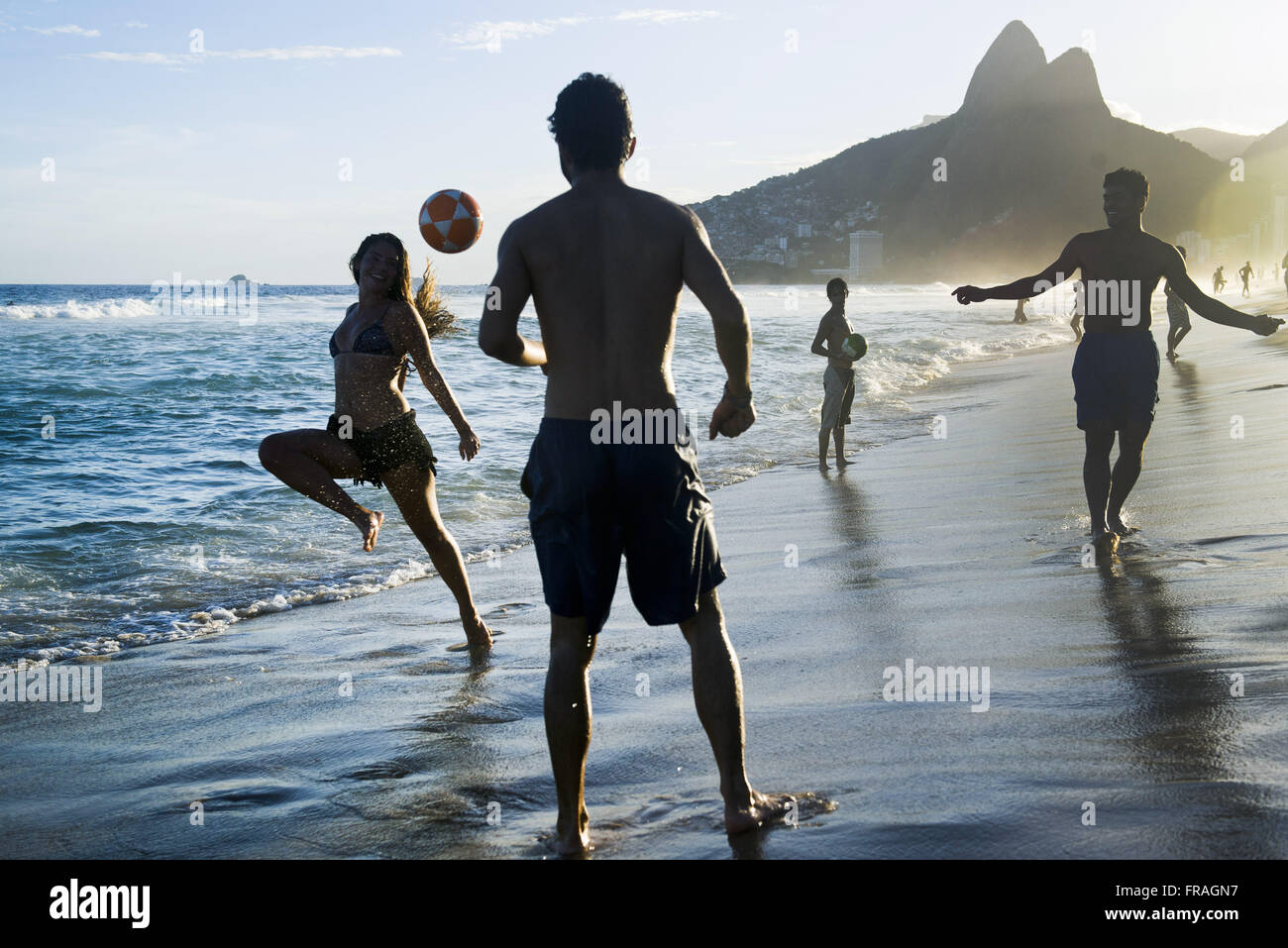 I bagnanti che giocano a calcio sulla spiaggia di Ipanema con i DOI Fratelli incidentali Foto Stock