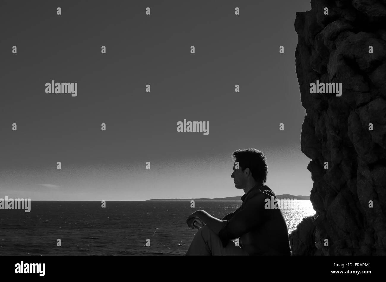 Un uomo seduto su una roccia e pensando al futuro Foto Stock