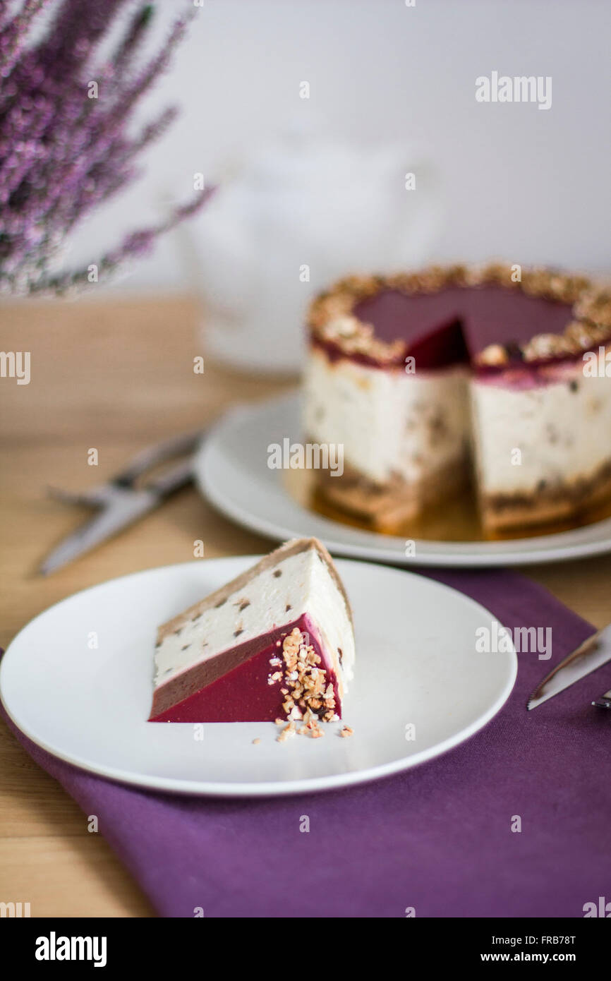 Pezzo di frutta cheesecake sulla piastra con tutta la torta in background Foto Stock