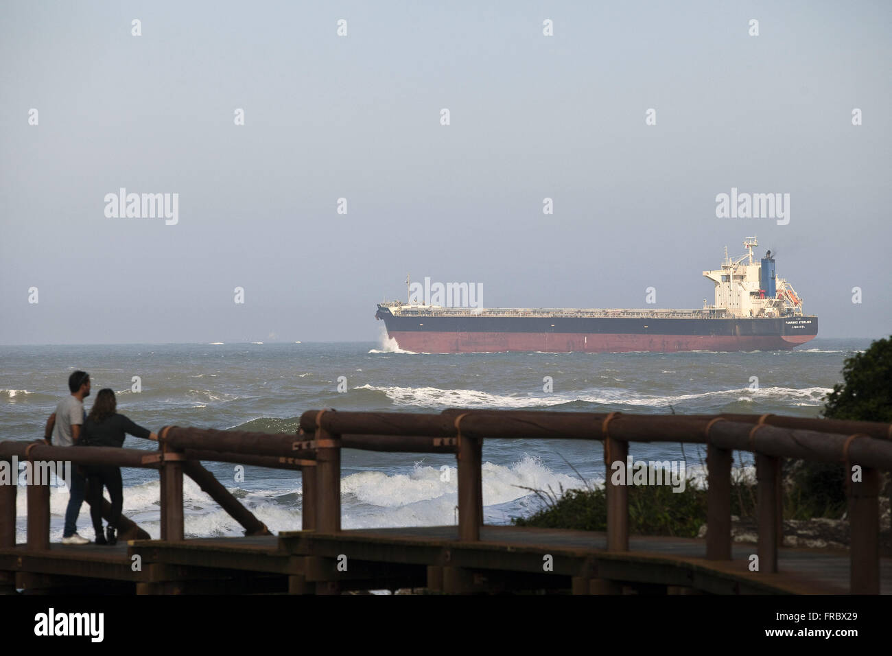 I turisti sul molo di legno a guardare la nave in avvicinamento alla Baia di Paranagua in Ilha do Mel Foto Stock