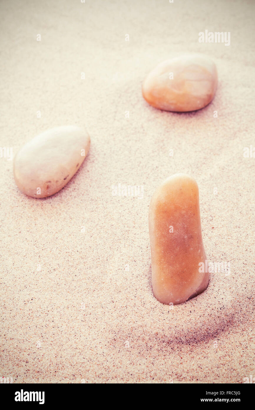 Vintage tonica pietre sulla sabbia in un divertente volto sorridente forma, creative sfondo naturale. Foto Stock
