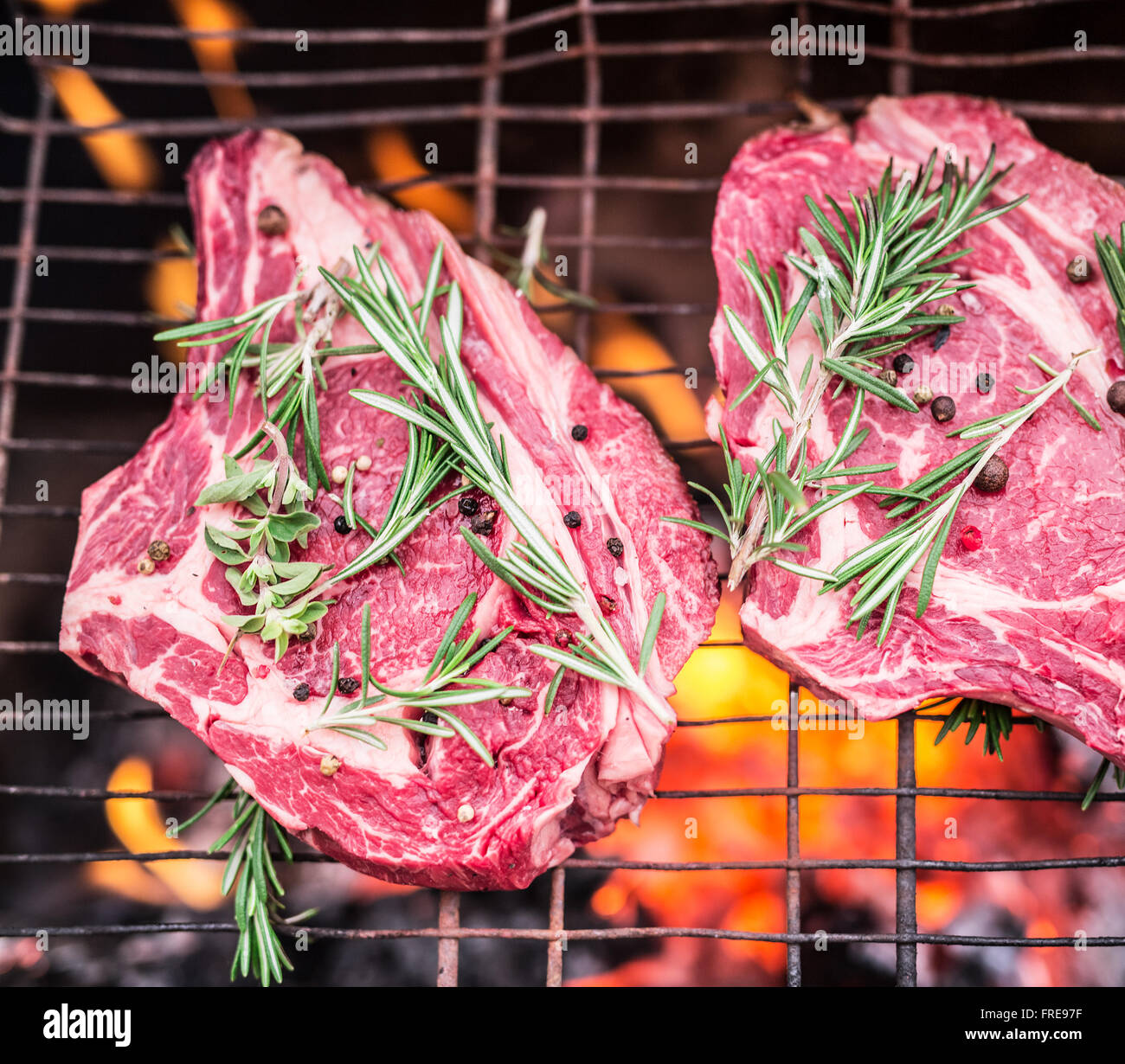 Occhio di nervatura bistecche e grill con un fuoco che brucia dietro di loro. Foto Stock