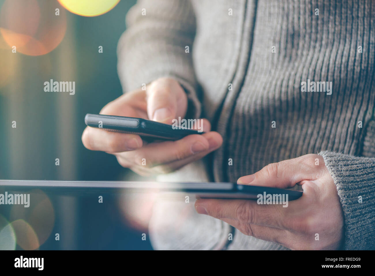 Smartphone e Tablet la sincronizzazione dei dati, l'uomo la sincronizzazione di file e documenti su personal wireless dispositivi elettronici a casa Foto Stock