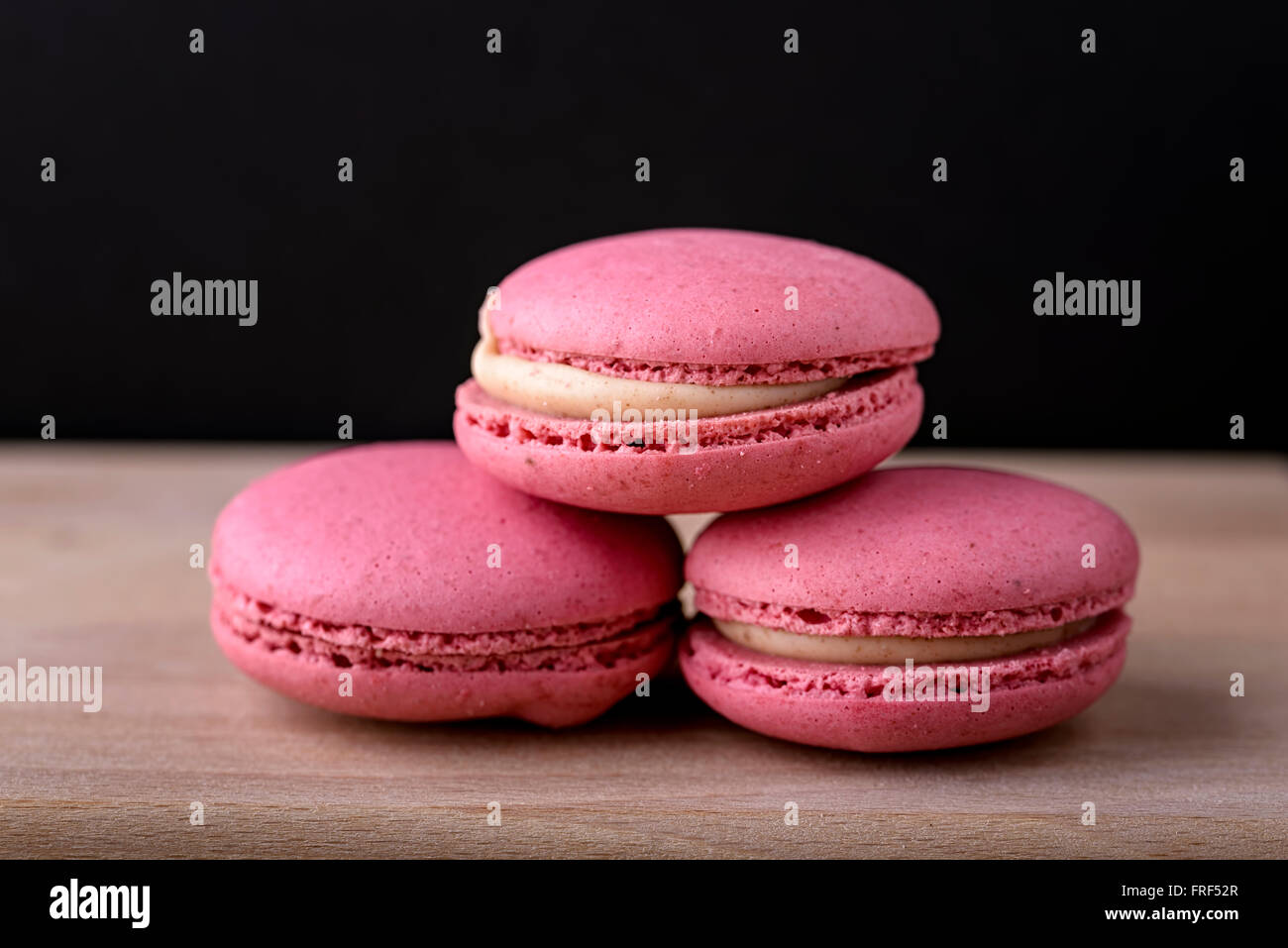 Tre macaron rosa su legno Foto Stock