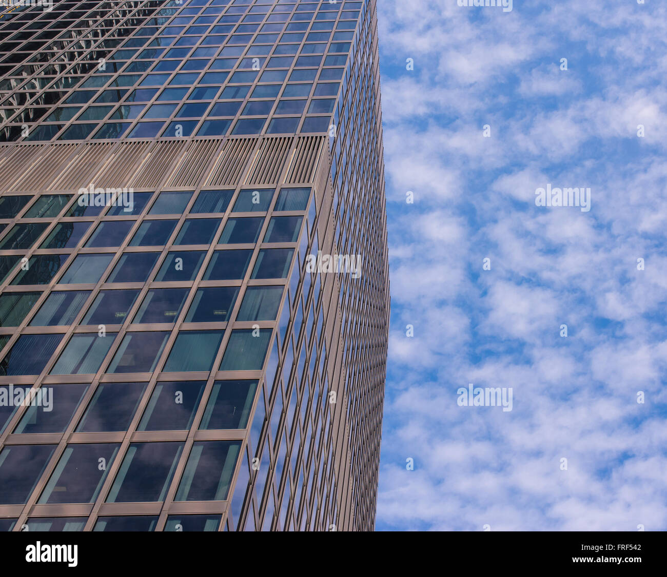 Facciata di vetro e moderno grattacielo con cielo blu e nuvole bianche in background. Girato da sotto. Foto Stock