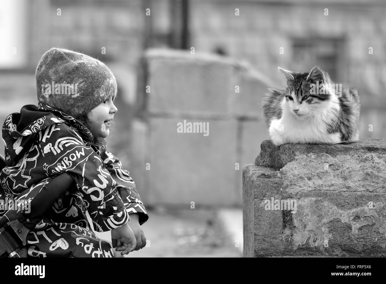 Giovane ragazza in passeggino con gatto randagio a Baku, capitale dell'Azerbaigian. Immagine in bianco e nero che mostrano affetto da ragazza per neonati Foto Stock