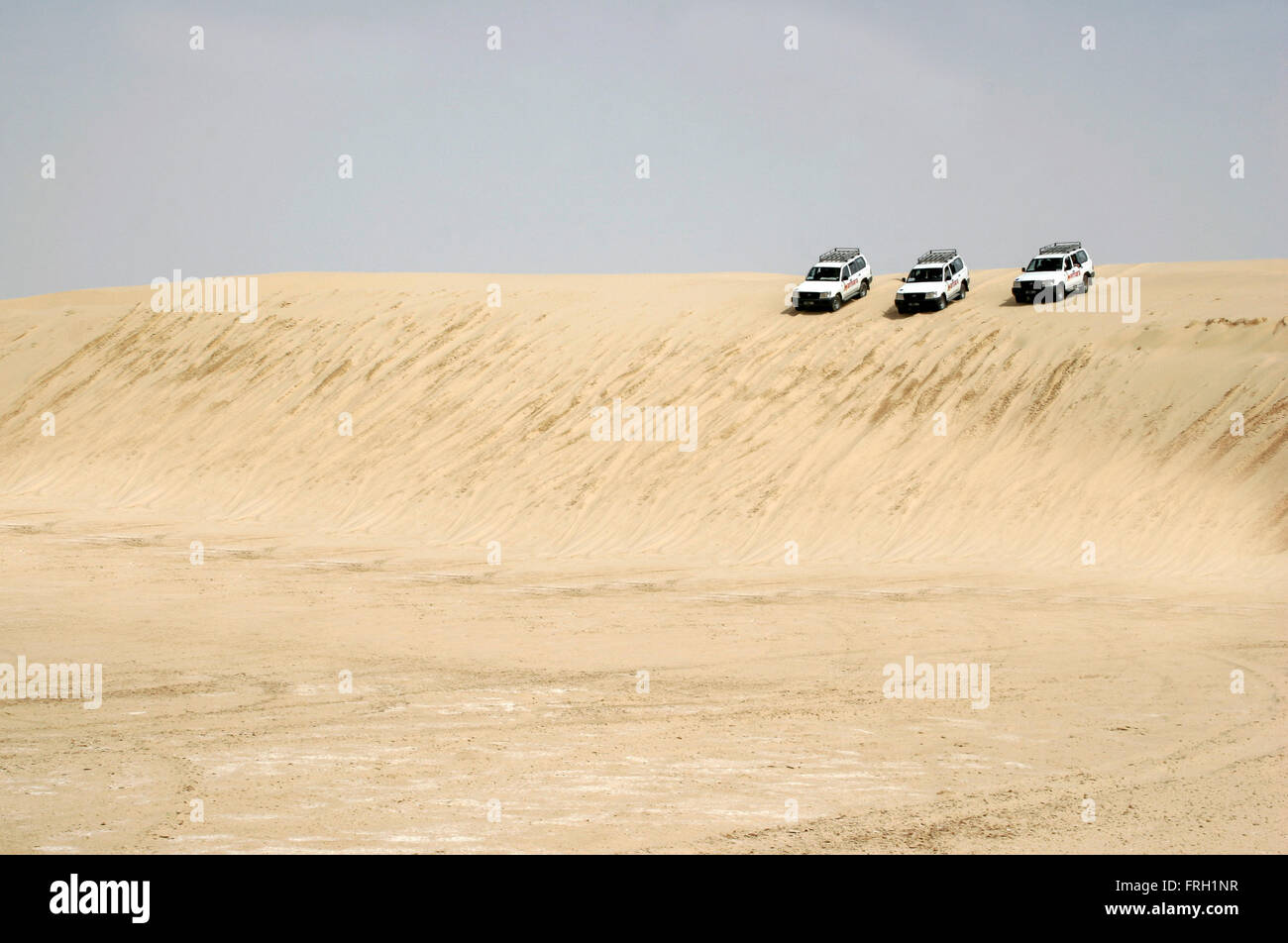 Tre 4 x 4 vetture allineate e pronto ad andare verso il basso a partire da una grande duna di sabbia al deserto del Sahara, Tunisia, Foto Stock