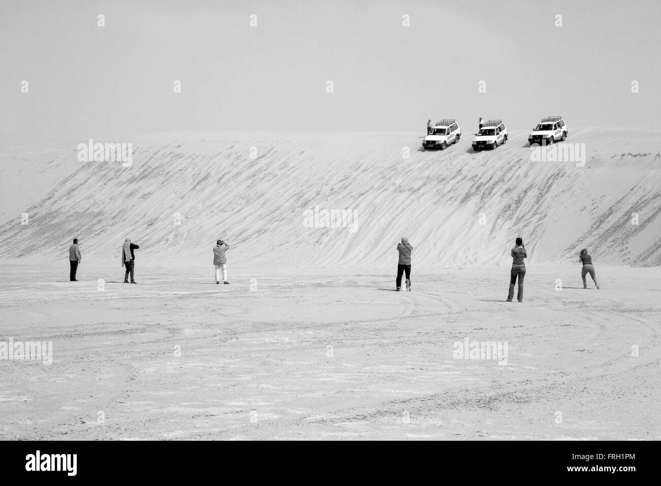 Sei turisti fotografare allineati tre 4 x 4 vetture voce verso il basso di una duna di sabbia al deserto del Sahara, in bianco e nero, Tuinisia Foto Stock