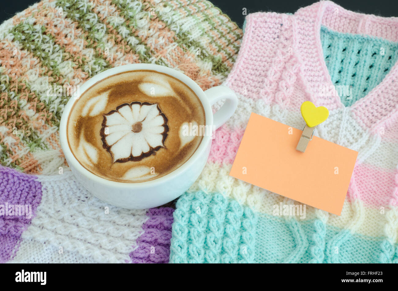Una tazza di latte art su un giubbotto in maglia di sfondo Foto Stock