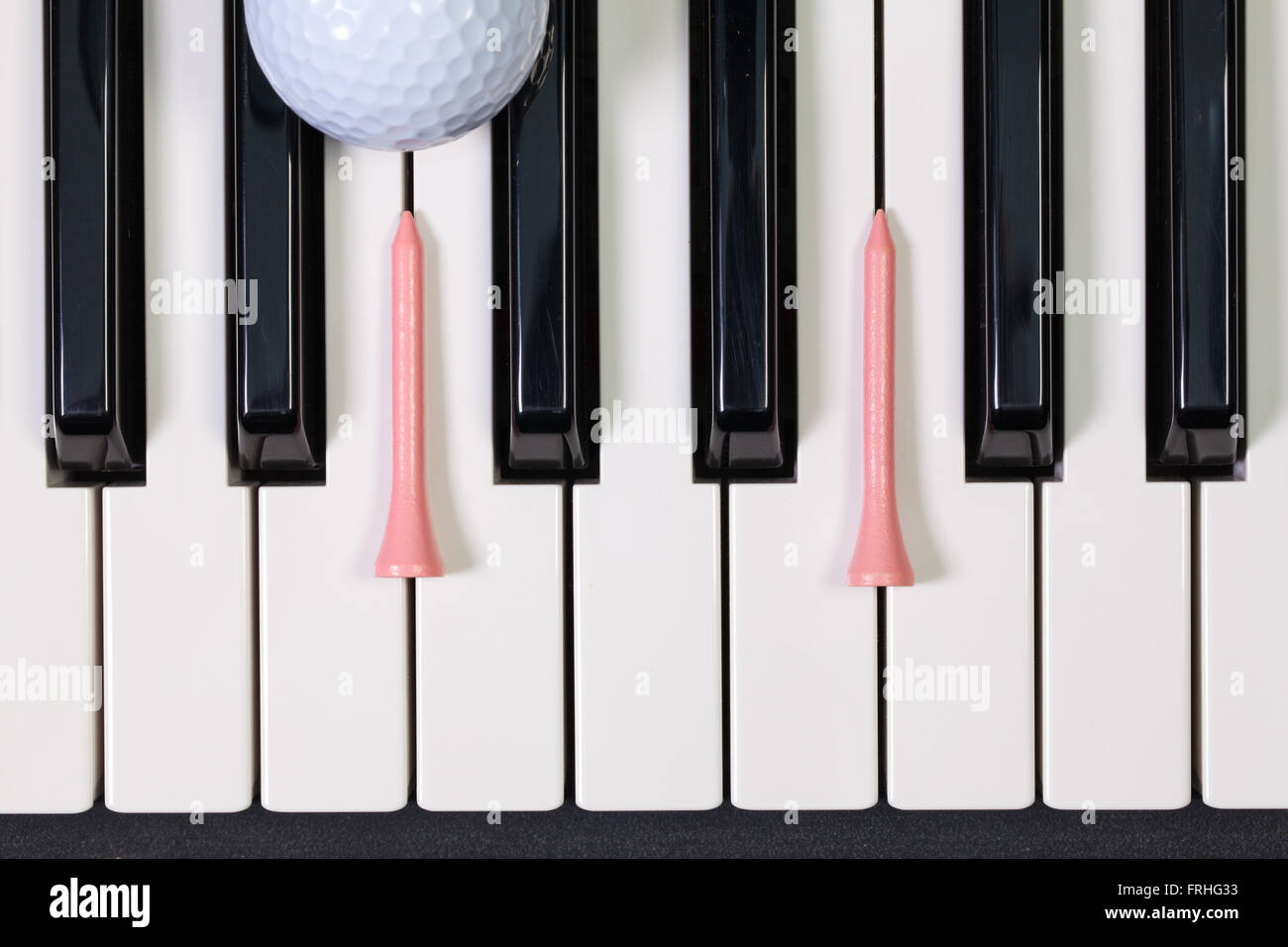 Virtuosi di gioco - Una tastiera di pianoforte e differenti palline da golf e tee di legno Foto Stock