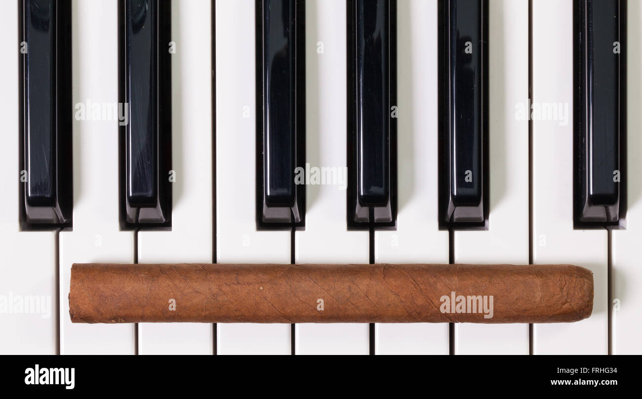 Dettaglio della tastiera di pianoforte e sigari di lusso Foto Stock