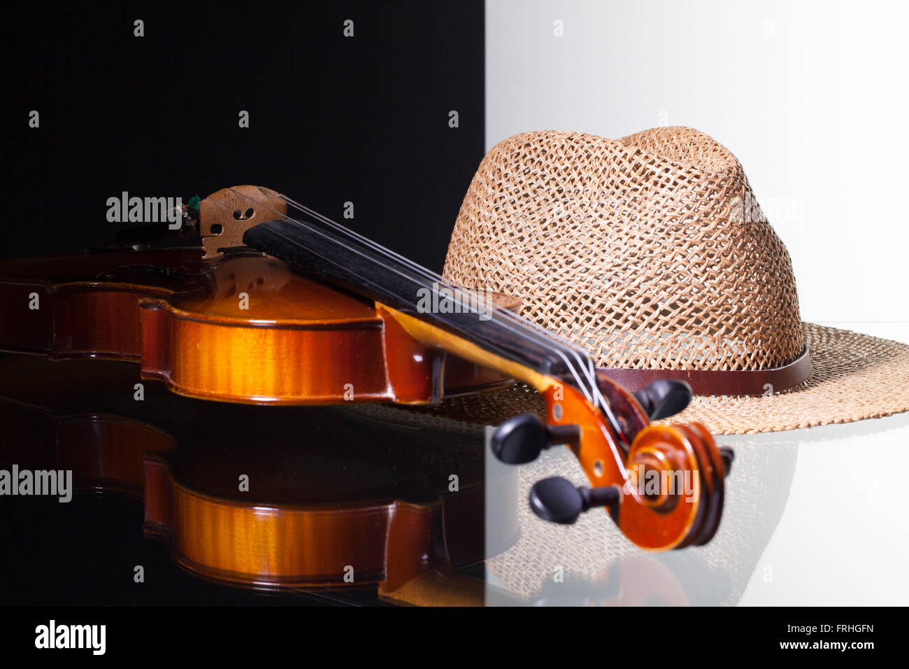Vecchio violino e cappello di paglia isolato in bianco e nero e sfondo scrivania in vetro Foto Stock