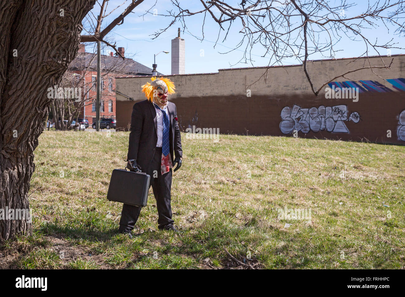 Detroit, Michigan - un uomo vestito come un clown squilibrate sorge in un lotto vacante lungo il percorso delle Marche du Nain Rouge. Foto Stock
