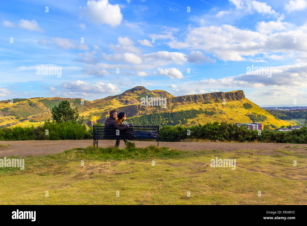 Una giovane coppia seduta sul banco a Carlton Hill, Edimburgo, Scozia, Regno Unito Foto Stock