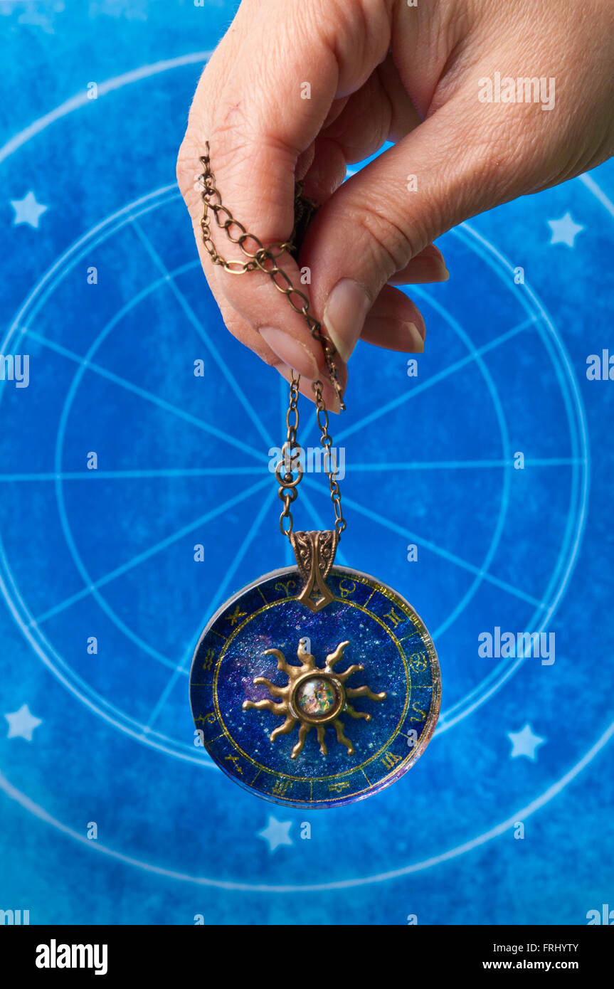 Mano che regge un medaglione astrologica Foto Stock