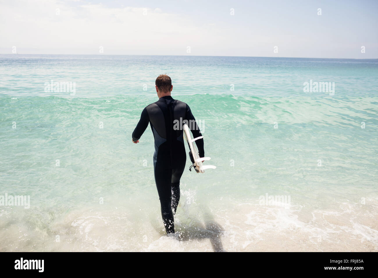 Surfer camminando verso il mare con una tavola da surf Foto Stock