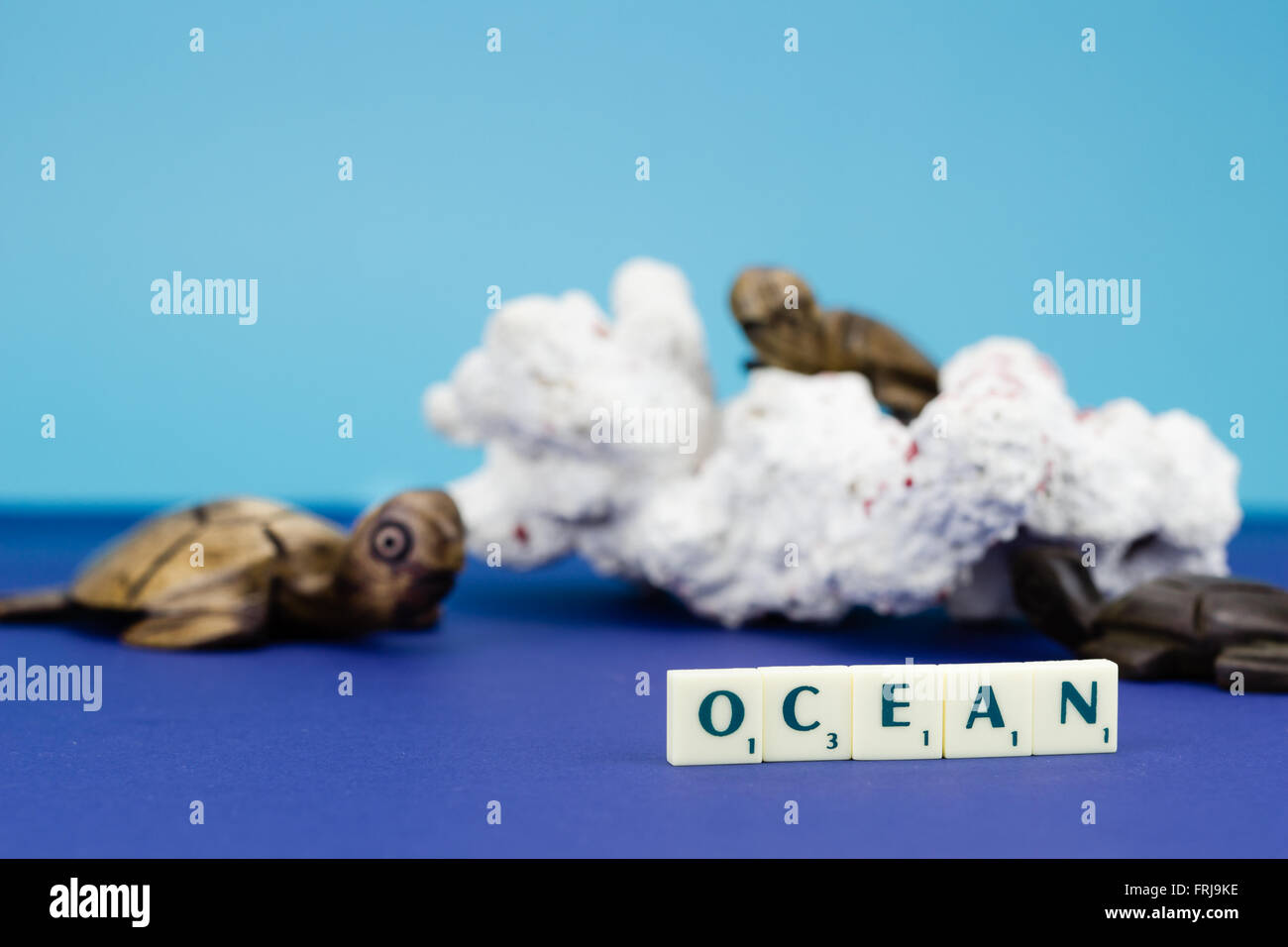 Tartaruga in legno figurine con corallo su sfondo blu Foto Stock
