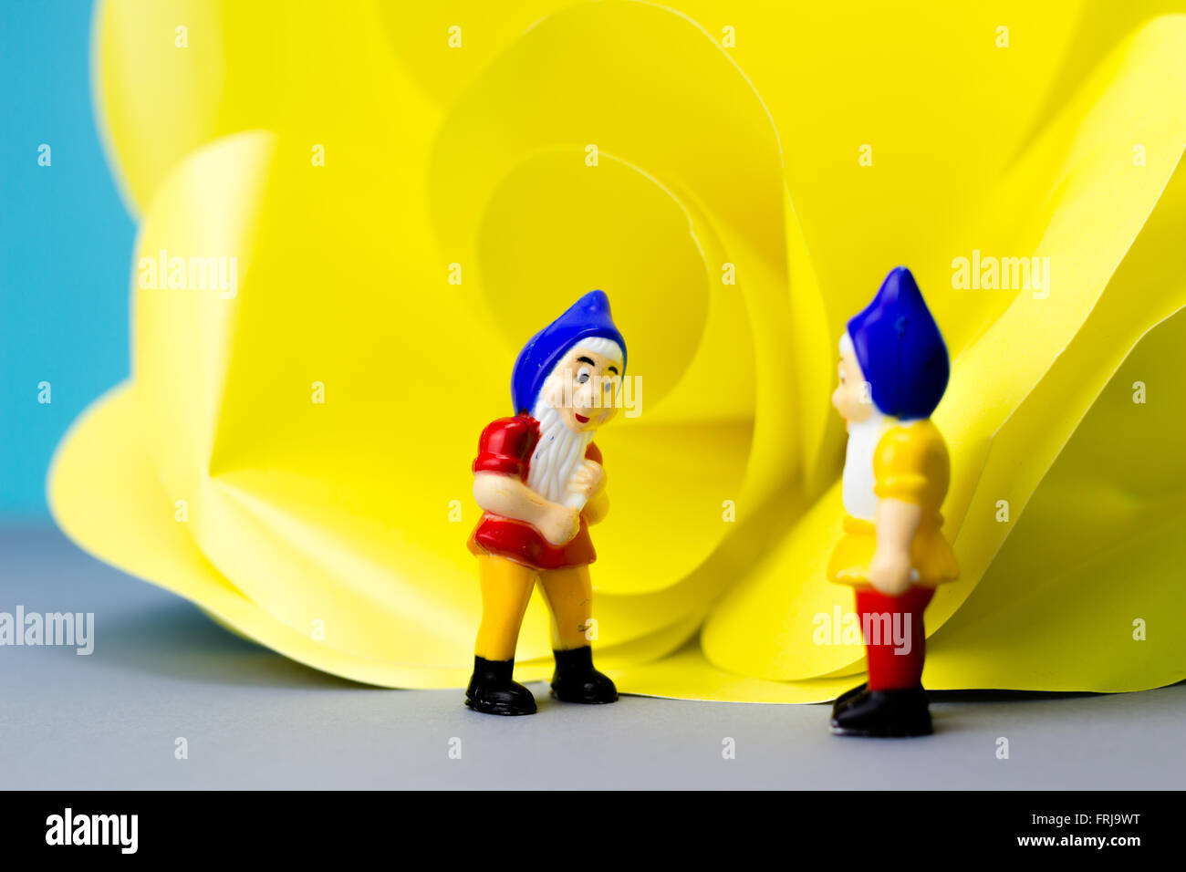 I nani in miniatura con il gigante fiore su sfondo blu Foto Stock