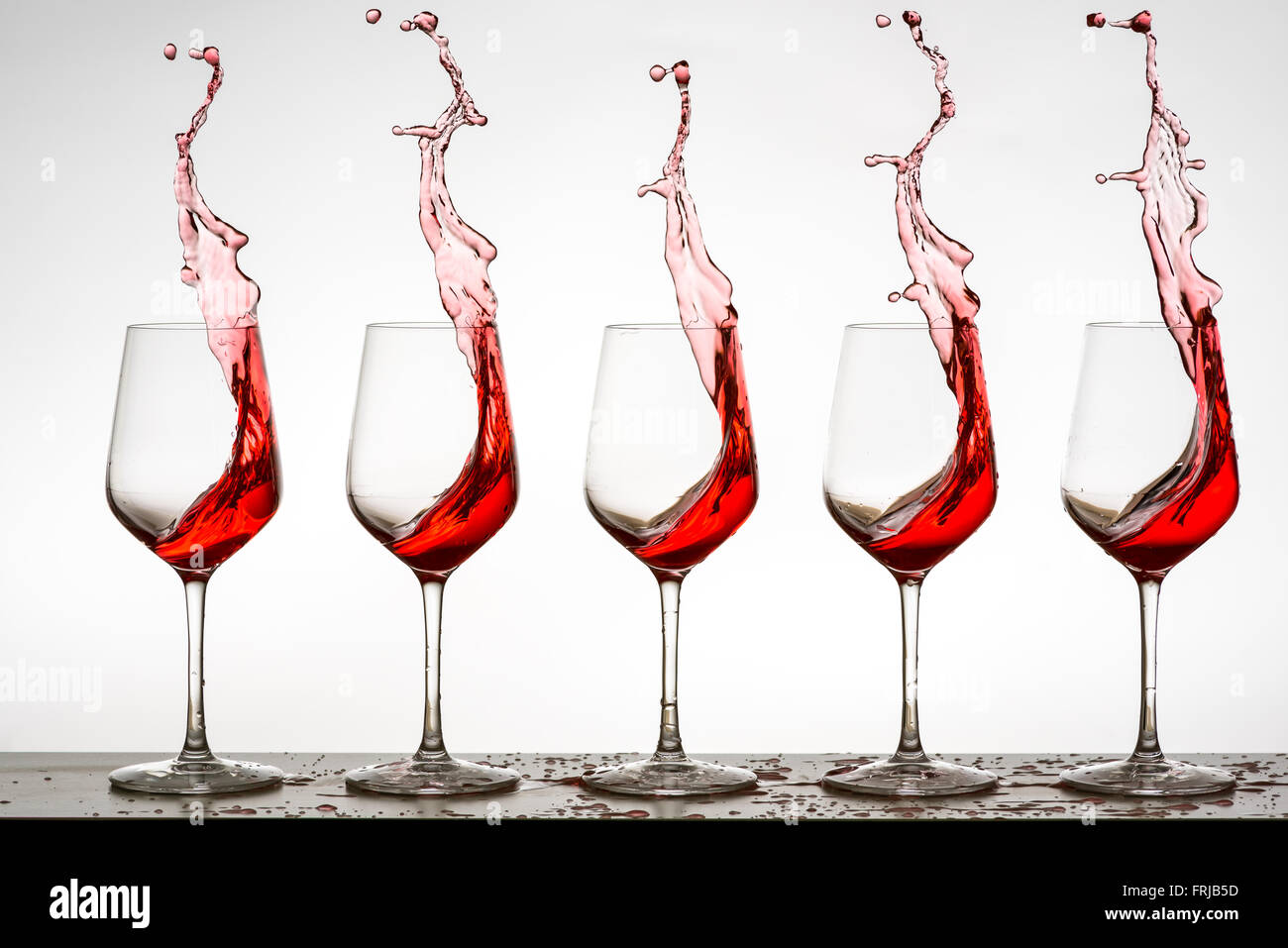 Vino rosso schizzi da 5 bicchieri di vino Foto Stock
