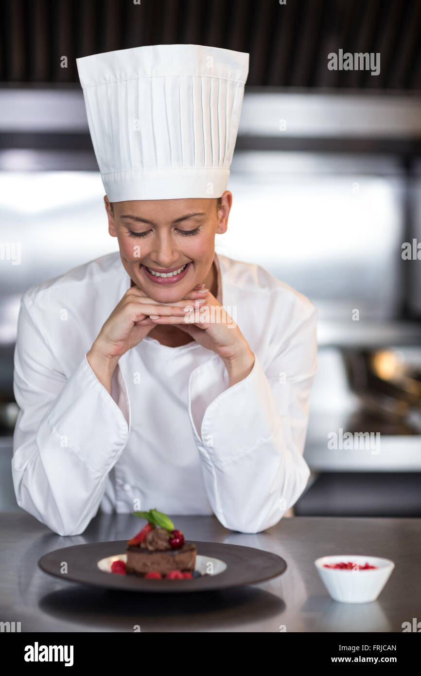 Lo chef femmina guardando la piastra di cibo in cucina Foto Stock