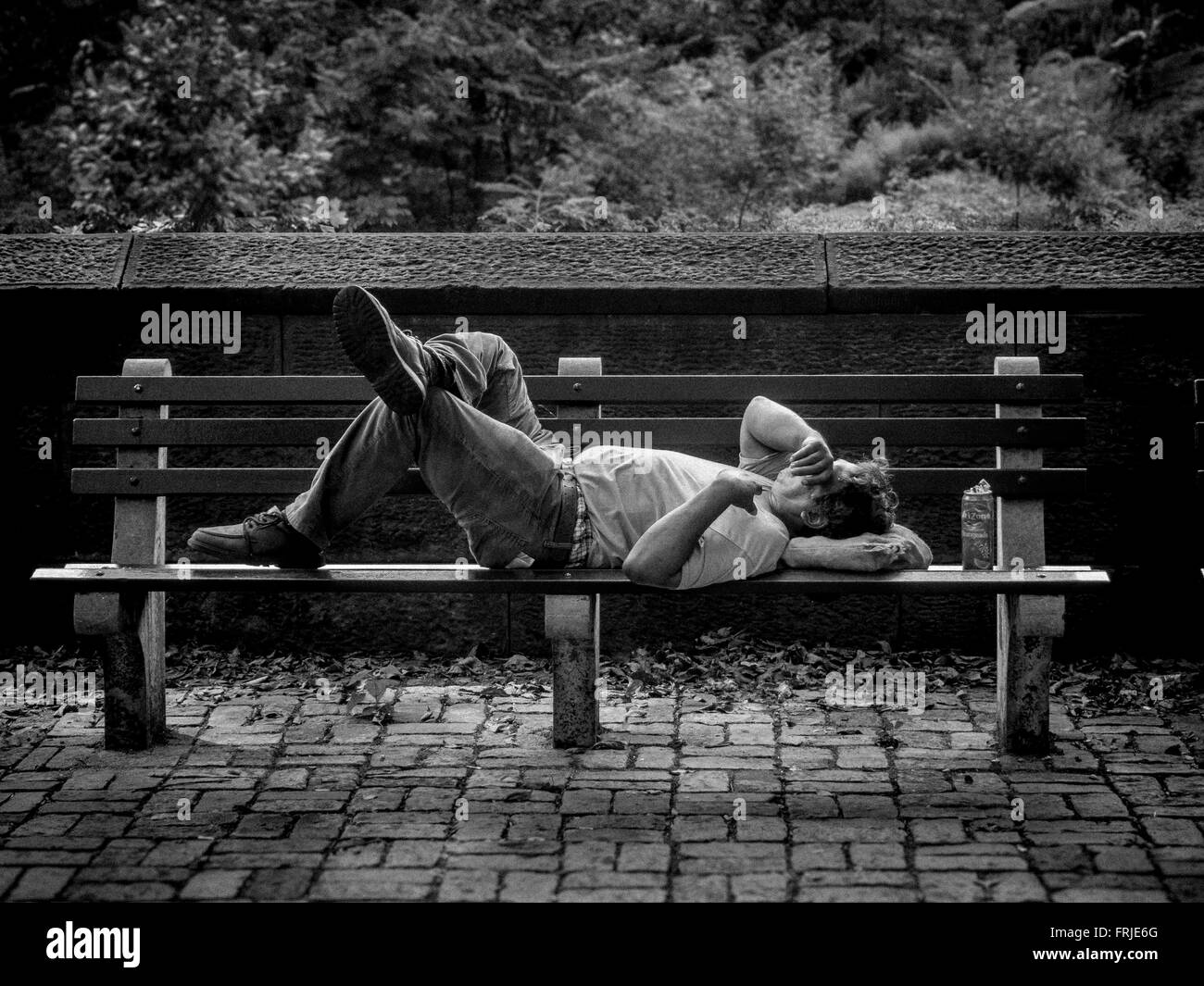 Uomo dorme sul banco di lavoro al di fuori del Central Park di New York City, Stati Uniti d'America Foto Stock