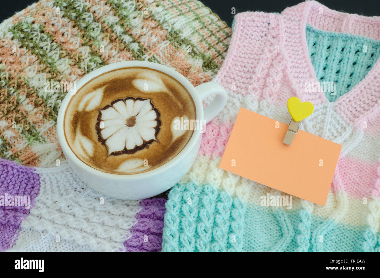 Una tazza di latte art su un giubbotto in maglia di sfondo Foto Stock