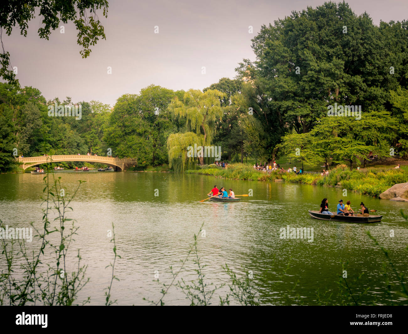 Barche a remi sul lago, Central Park, New York City, USA. Ponte di prua sullo sfondo Foto Stock