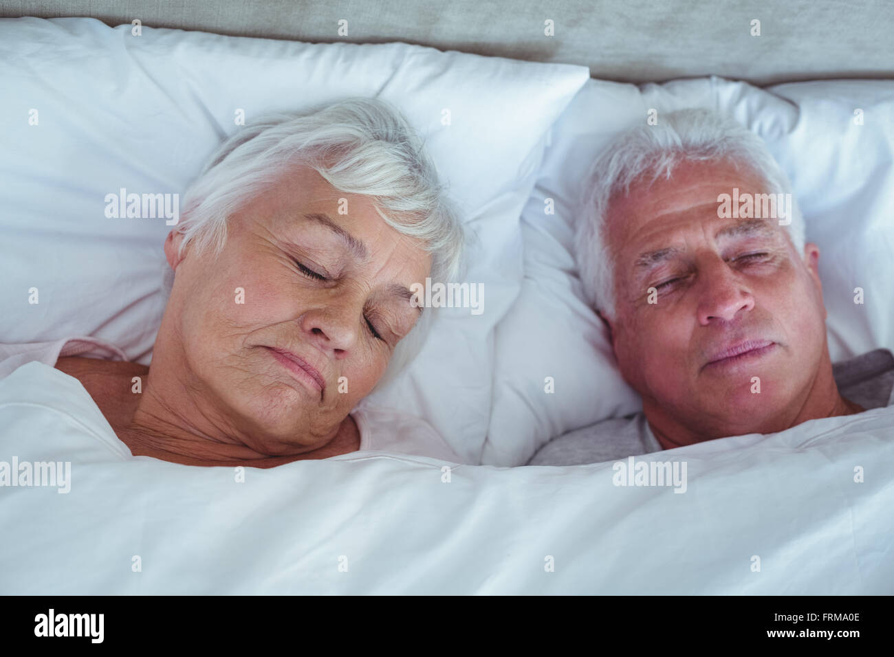 Coppia senior di dormire sul letto in camera Foto Stock