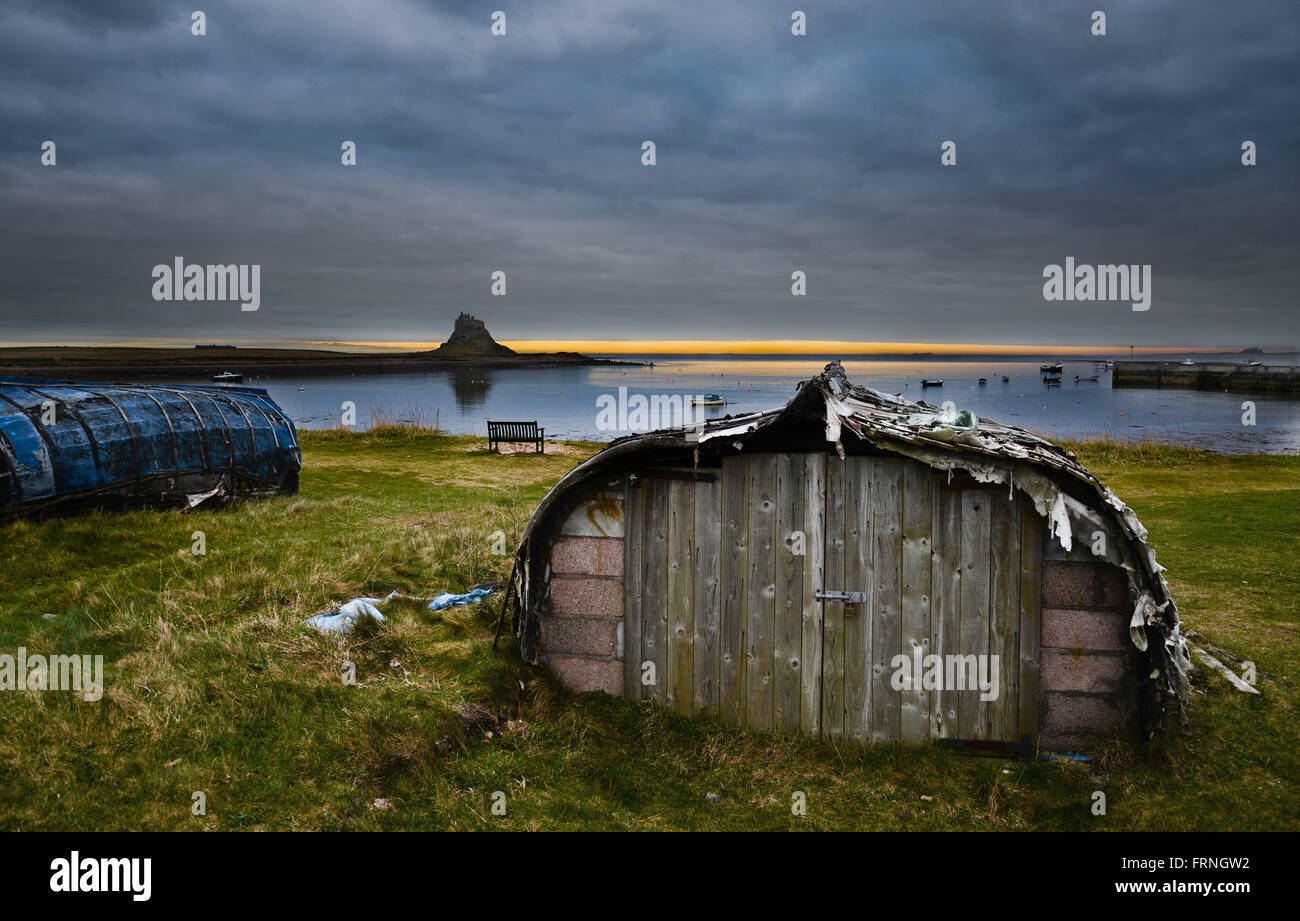 Lindisfarne Castle e le aringhe capannoni in barca che circondano il porto ancora oggi in uso dai pescatori per il lavoro e lo storage Foto Stock