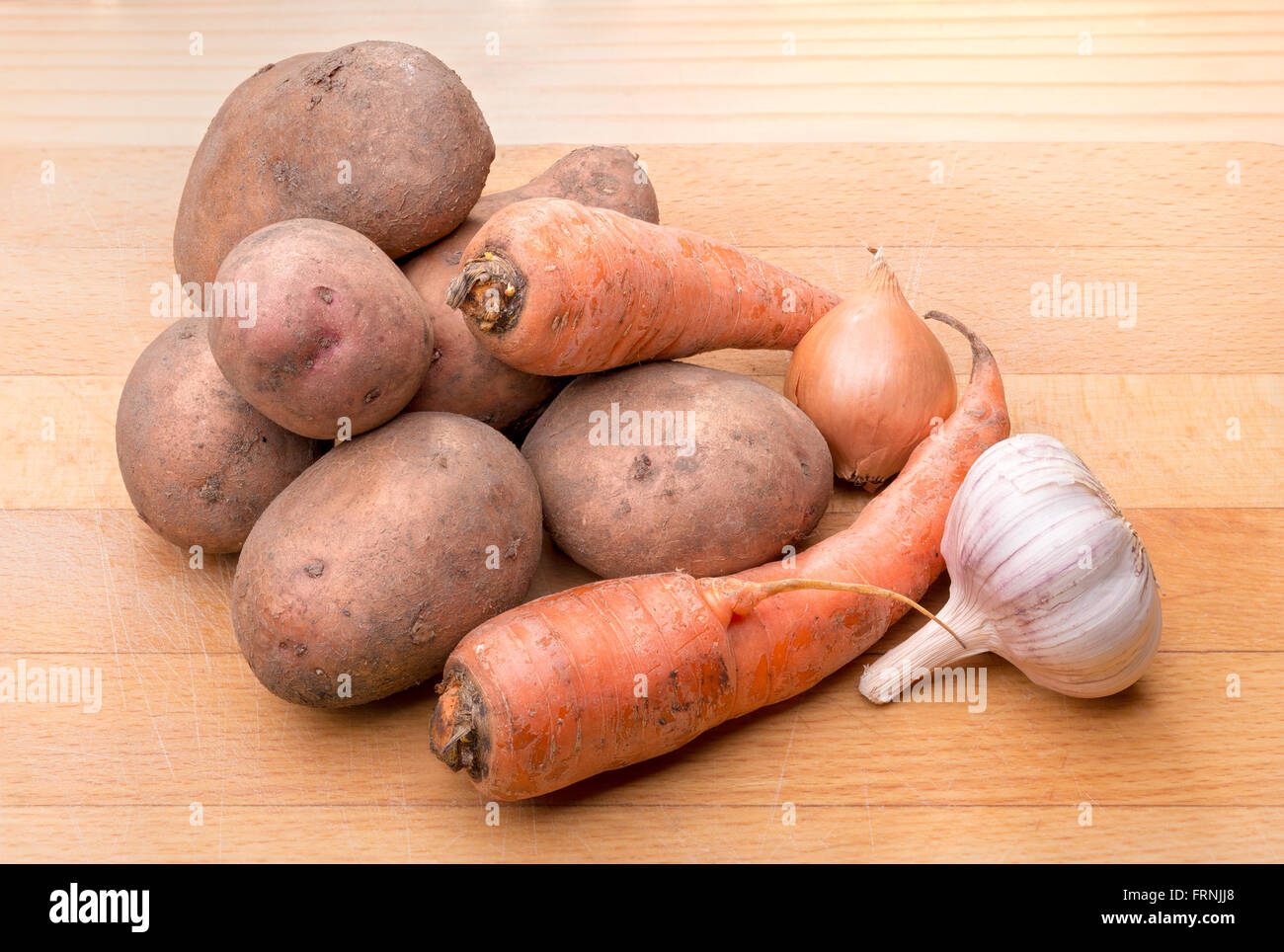 Patate naturale, oinion, aglio e carote su una tavola di legno cutboard Foto Stock