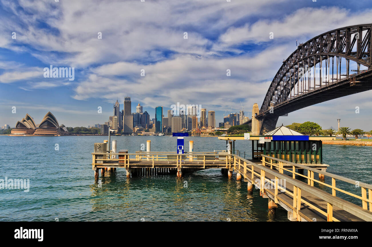 Il molo di legno per Sydney Harbour ferries con Sydney CBD grattacieli e Harbour Bridge in background. Foto Stock