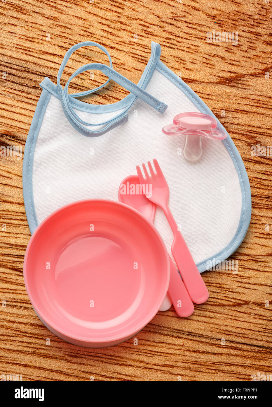 Ciotola del bambino, cucchiaio e forchetta con fantoccio e bavaglini Foto Stock