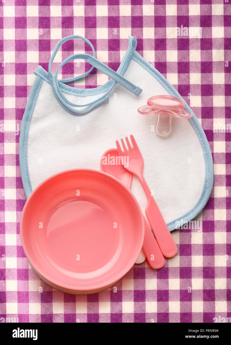Ciotola del bambino, cucchiaio e forchetta con fantoccio e bavaglini Foto Stock
