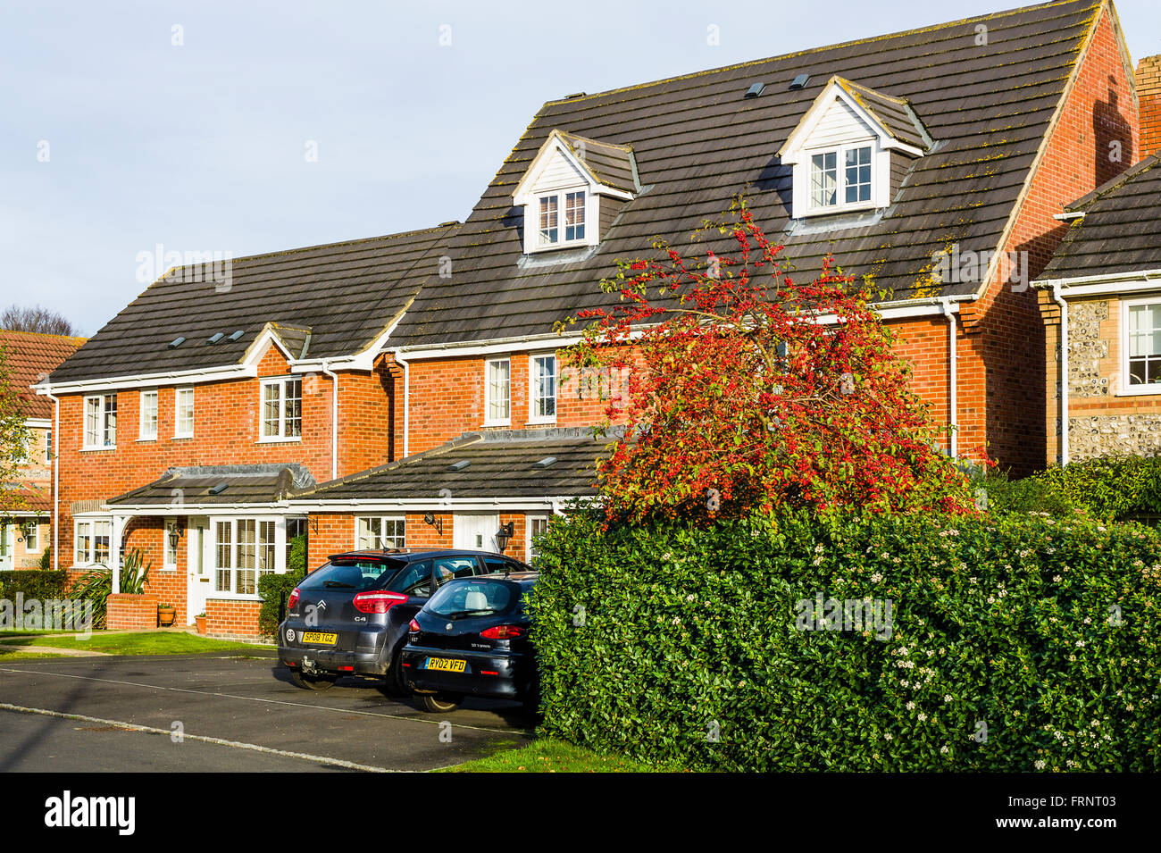 Diversi approcci per giardini anteriore su una moderna pressa britannica che mostra un piano aperto e uno chiuso con una siepe sempreverde Foto Stock