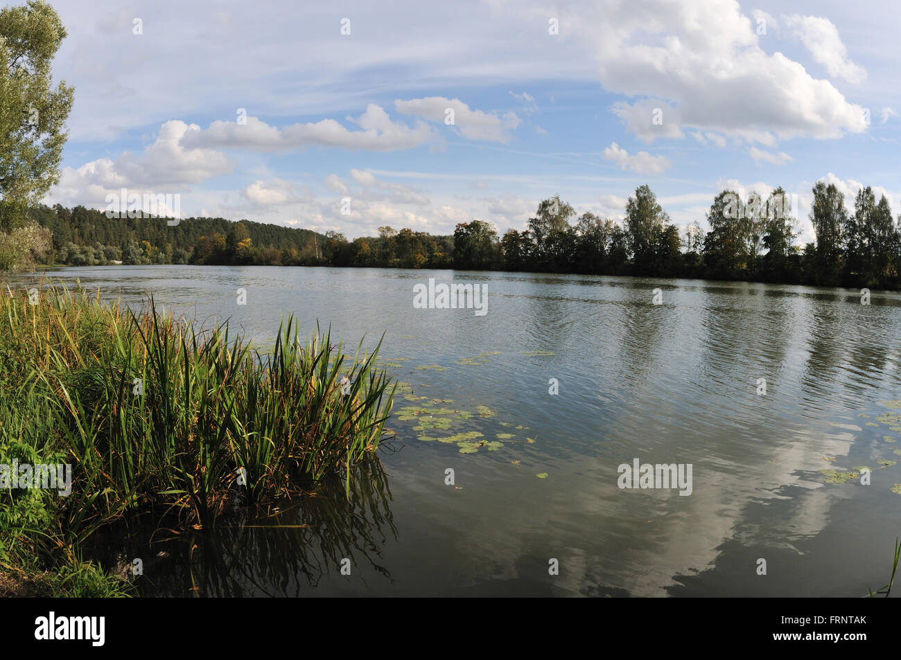La riflessione di nuvole nelle acque di un tranquillo fiume di pianura all'inizio dell'autunno Foto Stock