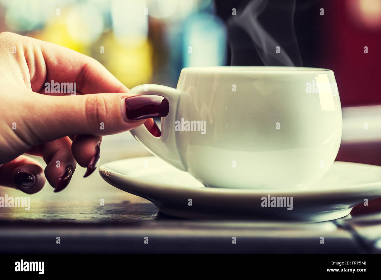 Donna con mano rosso chiodi curati tenendo una tazza di caffè. Foto Stock