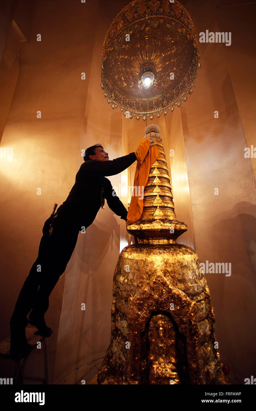 Un uomo in un tempio a Bangkok in Tailandia, rendendo la pulizia del tempio Foto Stock