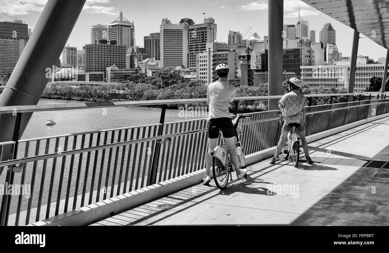 I ciclisti una sosta per ammirare la vista della città al di là del fiume Brisbane sulla buona volontà bridge Foto Stock